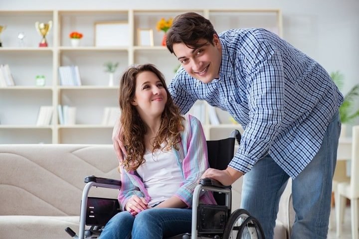 A support worker assisting a woman using a wheelchair in her living room